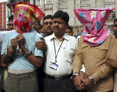 A policeman (C) stands with two men, who have their faces covered, inside the Lalbazar main police headquarters, in the eastern Indian city of Kolkata, December 6, 2008. Indian police said on Saturday they had arrested two men who helped the Mumbai attackers get mobile phone cards which they used for communications during their three-day rampage. [Xinhua/Reuters]