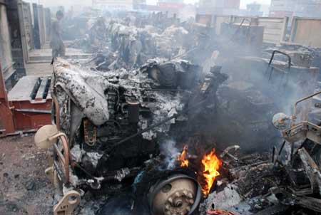 A Pakistani employee looks at burned-out trucks at a NATO terminal outside the northwestern city of Peshawar on Dec. 7. Taliban militants launched a pre-dawn raid on a NATO terminal in Pakistan on Sunday, torching more than 60 trucks carrying supplies for troops in Afghanistan and killing a guard, police said. [Xinhua/Reuters]