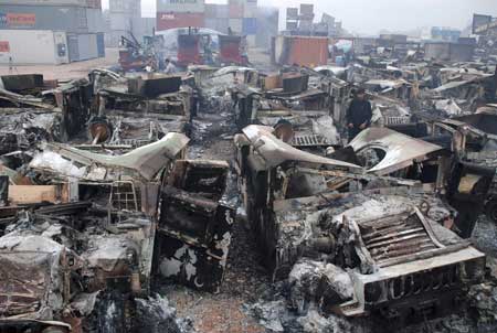 A Pakistani employee looks at burned-out trucks at a NATO terminal outside the northwestern city of Peshawar on Dec. 7. [Xinhua/Reuters]