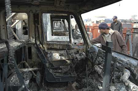 Pakistani employees inspect burned-out trucks at a NATO terminal outside the northwestern city of Peshawar on Dec. 7.[Xinhua/Reuters]