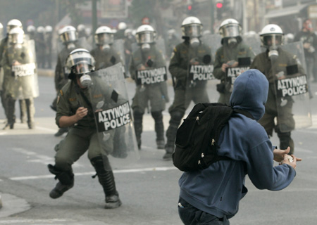 A protester prepares to throw a stone at riot policemen during riots in Athens December 7, 2008. Hundreds of demonstrators clashed with riot police in Athens and the northern Greek city of Thessaloniki on Sunday in a second day of protests at the shooting by police of a 15-year-old boy. [Agencies via China Daily] 