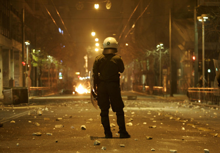 A policeman stands near burning barricades during riots in Athens December 7, 2008. Riots erupted across Greece after police shot dead a teenage boy in the Greek capital, police officials said. [Agencies]