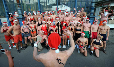 Santa Clause in swimming suits and Christmas hats sing Christmas carol druing a race in Budapest, Hungary, Dec. 7, 2008.[Xinhua]