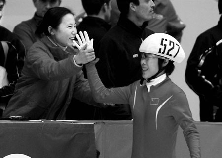 China's head coach Li Yan celebrates with one of her short track skaters, Zhou Yang, during a World Cup stop in Beijing on Sunday. [China Daily]