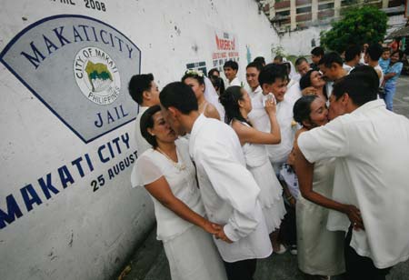 Filipino inmates kiss their brides during a mass wedding ceremony in a jail compound in Manila, the Philippines Dec. 8, 2008. [Xinhua]