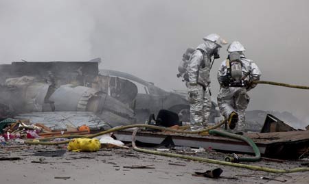 Firefighters battle flames next to the remains of a military jet that crashed into homes in the University City neighborhood of San Diego, California December 8, 2008. The military F18 jet crashed on Monday into the California neighborhood near San Diego after the pilot ejected, igniting two houses, officials said. [Agencies via China Daily] 