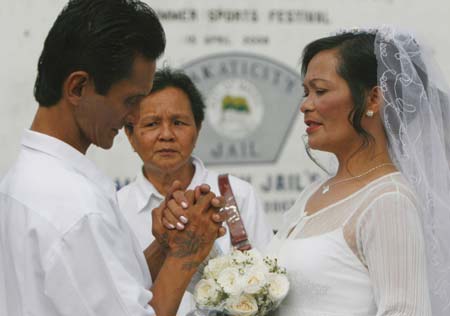 Filipino inmate Enrico Herrera (L), 49, holds his bride Virginia, 44, during a mass wedding ceremony in a jail compound in Manila, the Philippines Dec 8, 2008. The jail authorities annually organize a mass wedding ceremony for inmates, often during the Christmas season.[Xinhua] 