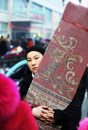 A Muslim girl carries a roll of carpet at a market in Urumqi, capital of northwest China's Xinjiang Uygur Autonomous Region, on Dec. 8, 2008. Muslims of Xinjiang Uygur Autonomous Region prepared to celebrate Eid-ul-Adha festival on Monday. [Xinhua]