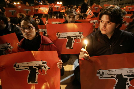 People holding posters featuring pistols gather in front Greece's parliament during a peaceful protest in Athens December 9, 2008. Riot police fought running battles with hundreds of protestors outside Greece's parliament on Tuesday while the opposition socialist party called for elections to end four days of protests. [Agencies via China Daily]