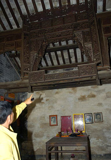 A room in a traditional house at Baoping village, Hainan Island contains a well preserved shrine exquisitely engraved with traditional Chinese dragon, phoenix, crane, pine, plum and bamboo motifs. [Xinhua, December 9, 2008] 