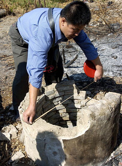 A researcher measures an ancient well belonging to Ming and Qing dynasty houses at Baoping village, Hainan Island. [Xinhua, December 9, 2008]