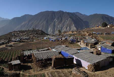 Photo taken on Dec. 8, 2008 shows the collapsed houses (rear) and the temporary houses in Luobozhai Village of Yanmen Township, the quake-hit Wenchuan County, southwest China's Sichuan Province. Luobozhai, less than 10 kilometers from the county seat, is the biggest Qiang ethnic village existing in China. [Xinhua]
