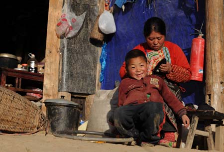 A Qiang ethnic boy smiles in front of his mother in Luobozhai Village of Yanmen Township, the quake-hit Wenchuan County, southwest China's Sichuan Province, Dec. 8, 2008.