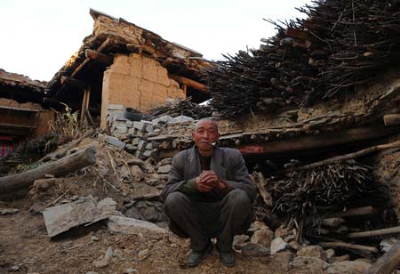 Zhang Xianzhong, a resident of Luobozhai, poses for a photo in front of his house collapsed in the earthquake, in Luobozhai Village of Yanmen Township, the quake-hit Wenchuan County, southwest China's Sichuan Province, Dec. 8, 2008. 