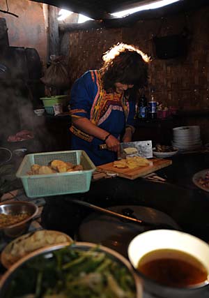 Wang Xiaoying, a Qiang ethnic resident, cooks dinner in a temporary kitchen in Luobozhai Village of Yanmen Township, the quake-hit Wenchuan County, southwest China's Sichuan Province, Dec. 8, 2008. Luobozhai, less than 10 kilometers from the county seat, is the biggest Qiang ethnic village existing in China. 