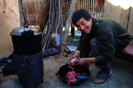 A man cooks preserved meet for the up-coming new year in Luobozhai Village of Yanmen Township, the quake-hit Wenchuan County, southwest China's Sichuan Province, Dec. 8, 2008. Luobozhai, less than 10 kilometers from the county seat, is the biggest Qiang ethnic village existing in China. 