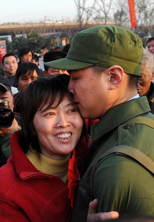 A recruit for the People's Liberation Army kisses his mother before leaving to start his service, at a train station in Nanjing, East China's Jiangsu Province, December 10, 2008. [Xinhua]