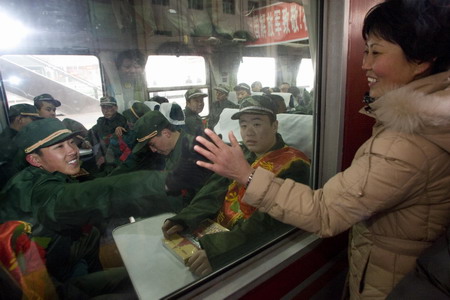 A recruit for the People's Liberation Army waves goodbye to his mother before leaving to start his service, at a train station in Tianjin, December 10, 2008. [Xinhua]