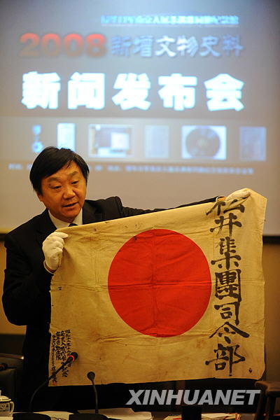 Zhu Chengshan, curator of the Memorial Hall of the Victims of the Nanjing Massacre shows the Japanese flag that was used when Japanese troops marched into Nanjing, then the capital of China, in Nanjing, east China's Jiangsu Province, on Dec. 11, 2008. (Xinhua Photo)