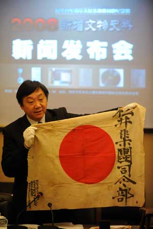 Zhu Chengshan, curator of the Memorial Hall of the Victims of the Nanjing Massacre shows the Japanese flag that was used when Japanese troops marched into Nanjing, then the capital of China, in Nanjing, east China's Jiangsu Province, on Dec. 11, 2008. [Xinhua]