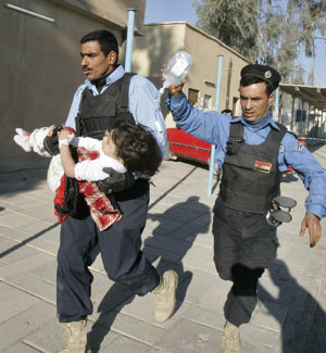 Iraqi policemen rush a child wounded in a bomb attack into a hospital in Kirkuk, 250 km (155 miles) north of Baghdad December 11, 2008. 