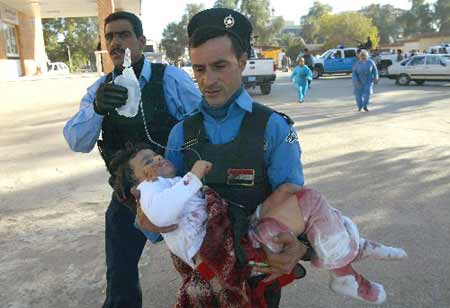 Iraqi policemen rush a child wounded in a bomb attack into a hospital in Kirkuk, 250 km (155 miles) north of Baghdad December 11, 2008.