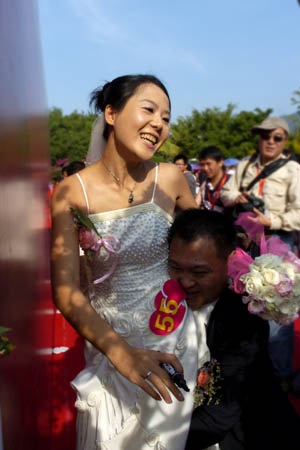 A groom carrying his bride in the arms signs his name on a board at Sanya City, south China's Hainan Province, Dec. 12, 2008. A total of 99 newly weds and old couples from home and abroad came to the Huge Rock with Four Characters of 'Tian Ya Hai Jiao (the Remotest Corner of the World)' on the coast south of Sanya City, to attend the 12th Sanya International Wedding Celebration Festival on Friday. (Xinhua/Guo Cheng)