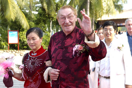 A 75-year-old French man waves as his 45-year-old Chinese wife smiles at Sanya City, south China's Hainan Province, Dec. 12, 2008. They came here from Shanghai to celebrate the 10th anniversary of their marriage. A total of 99 newly weds and old couples from home and abroad came to the Huge Rock with Four Characters of 'Tian Ya Hai Jiao (the Remotest Corner of the World)' on the coast south of Sanya City, to attend the 12th Sanya International Wedding Celebration Festival on Friday. (Xinhua/Guo Cheng)