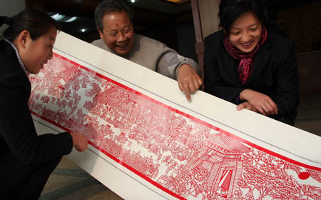 Li Tongzhu (C), a 64-year-old retired man, shows his paper-cut work of 'Riverside scenes at the Qingming Festival' in Zaozhuang City, east China's Shandong Province, Dec. 13, 2008.