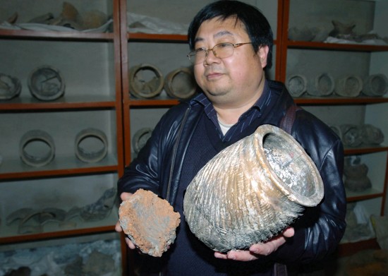  Wang Shougong, archaeologist and deputy director of the Institute of Cultural Relics and Archaeology of Shandong Province, displays a restored galeiform vessel. The vessel is 30 centimeters in height and 20 centimeters in diameter. [Wu Zengxiang/Xinhua]