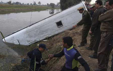 Policemen stand next to the wreckage of a bus in El Minya, about 220 km (150 miles) southwest of Cairo, December 14, 2008.