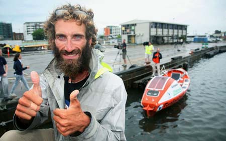 Handout picture shows Italian adventurer Alex Bellini gesturing in front of his row boat (R) after arriving in the port city of Newcastle, about 120 km (75 Miles) north east of Sydney, December 13, 2008. 