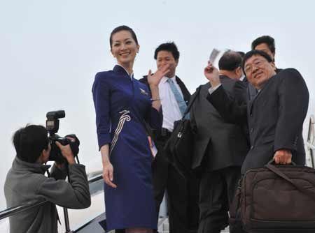 Tseng Yee-lun (2nd L), a Shenzhen Airlines air hostess from southeast China's Taiwan, gestures as passengers board the plane at the Shenzhen Airport in Shenzhen, south China's Guangdong Province, Dec. 15, 2008. 
