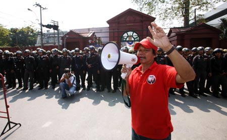 A protestor delivers a speech to his counterparts as riot police look on outside the parliment building in Bangkok, capital of Thailand, Dec. 15, 2008. Supporters of former Thai Prime Minister Thaksin Shinawatra held a rally here on Monday after Democrat Party leader Abhisit Vejjajiva was elected as Thailand's new prime minister at the parliament. (Xinhua/Niu Xiaolei) 