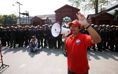 A protestor delivers a speech to his counterparts as riot police look on outside the parliment building in Bangkok, capital of Thailand, Dec. 15, 2008. Supporters of former Thai Prime Minister Thaksin Shinawatra held a rally here on Monday after Democrat Party leader Abhisit Vejjajiva was elected as Thailand's new prime minister at the parliament.