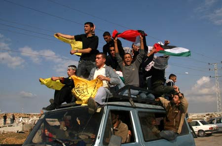 Palestinian people raise flags as they welcome Palestinian prisoners who were freed, at Erez crossing point in northern Gaza Strip, Dec. 15, 2008.