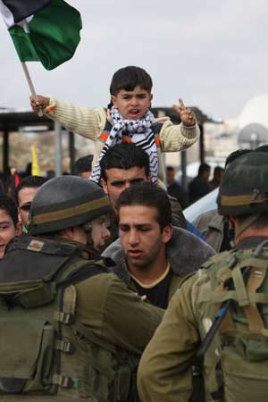 A Palestinian boy waves flag while waiting for the arrival of the Palestinian prisoners at the Beitunya checkpoint near Ramallah, Dec. 15, 2008. Israel released 224 Palestinians held in its prisons on Monday, nearly a week later than planned, in a move it described as a goodwill gesture to Palestinian President Mahmoud Abbas. 