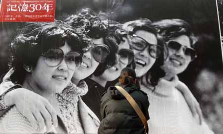 A girl appreciates an old photo taken in 1980 at an exhibition featuring China's 30 years' reform and opening-up at Wangfujing Street in Beijing, China, on Dec. 16, 2008. The photo exhibition presenting near 800 pictures in memory of the past 30 years'development was unveiled here on Tuesday. 