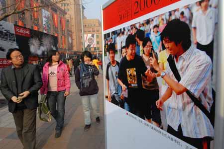 People walk past a photo taken in 2007 at an exhibition featuring China's 30 years' reform and opening-up at Wangfujing Street in Beijing, capital of China, on Dec. 16, 2008. The photo exhibition presenting near 800 pictures in memory of the past 30 years' development was unveiled here on Tuesday.