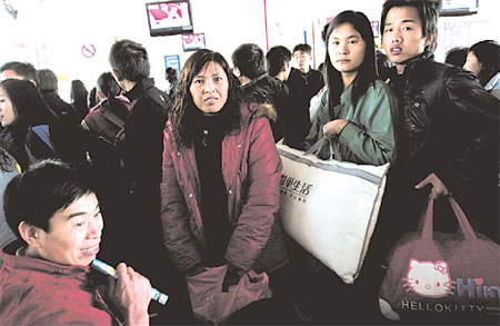 Migrant workers wait for trains in a Dongguan railway station to return to their homes in Henan province. [China Daily]