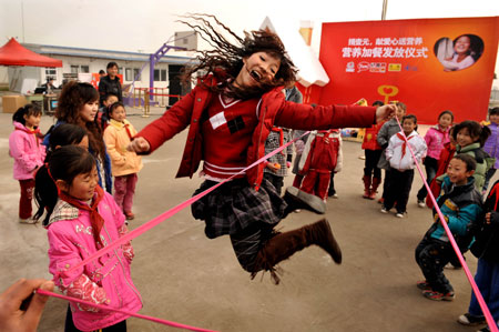 Volunteer Xia Yujie (center) jumps while playing a game called 'ribbon jumping' with students of Qingping Primary School in Mianzhu, Sichuan Province on Tuesday. Xu attended a volunteer program aimed at boosting health awareness among local students caught in the deadly May 12 earthquake. 