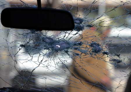 A senior woman walks by a car damaged by Qassam rocket in Sderot, southern Israel, Dec. 18, 2008. 