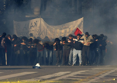 Protesters try to cover from teargas thrown by police during riots in central Athens December 18, 2008.