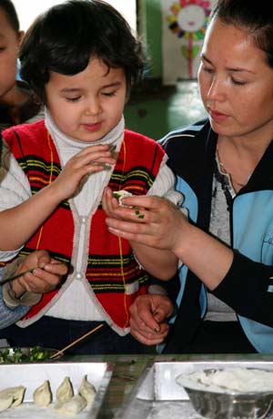 A girl makes dumplings with her mother to celebrate the upcoming winter solstice day at a kindergarten in Hami, northwest China's Xinjiang Uygur Autonomous Region, Dec. 19, 2008. As the Chinese tradition, people eat dumplings to celebrate the winter solstice day. [Cai Zengle/Xinhua]