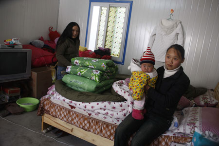 Wu Jia, who lost her husband in the May 12 earthquake, holds her baby in her pre-fabricated house in Pingwu county, Sichuan Province. [China Daily] 