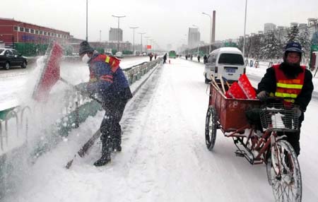 Workers clear snow on a street in Tianjin, north China, Dec. 21, 2008. A heavy snowfall hit Tianjin Saturday night. 