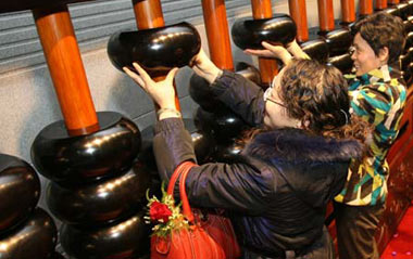 Visitors try to lift the beads of the huge abacus, one of which weighs 6.3 kilograms, at China Abacuses Museum in Nantong, east China's Jiangsu Province, Dec. 20, 2008. The abacus, 781 centimeters in length and 1.81 centimeters in height, has been on display here since Saturday.