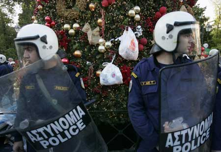 Policemen stand guard in front of a Christmas tree during a demonstration in Athens Dec. 20, 2008. People protesting over the fatal shooting of a youth in central Athens two weeks ago, threw garbage at the Christmas tree at central Syntagma square.