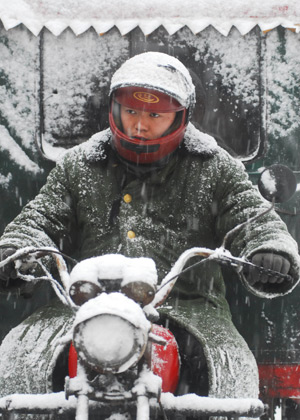 A man drives motorcycle in snow on a street in Yantai city, east China's Shandong Province, Dec. 21, 2008.