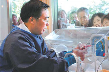Zhang Hemin puts a panda cub into an incubator at Wolong reserve's breeding center in Sichuan Province. [China Daily]